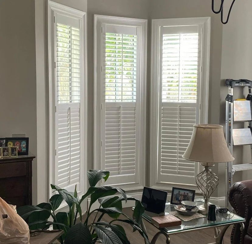 Three tall windows in white plantation shutters