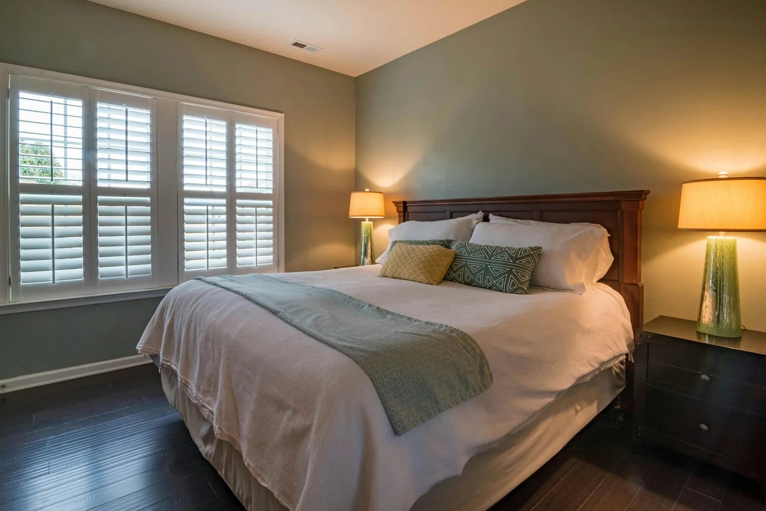 Bedroom with a wooden headboard and white plantation shutters