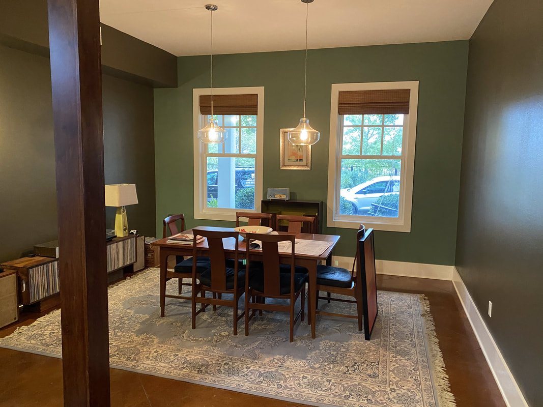Green dining room with woven grass shades and pendant lights