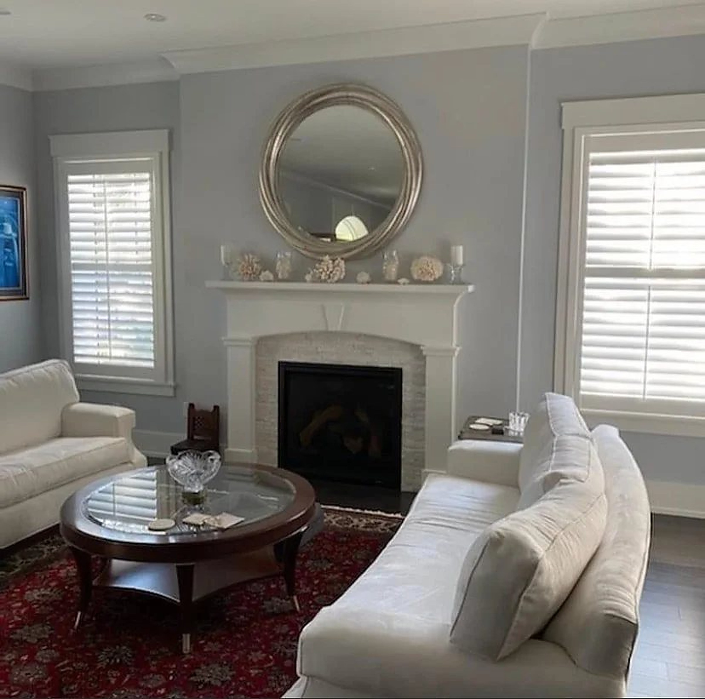 Living room fireplace framed by white plantation shutters